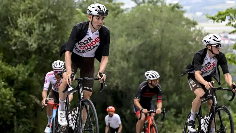 Radfahrer im Rennen bei der Dauphiné Rundfahrt. Ein Fahrer in weißem Trikot mit "AG2R CITROEN" Aufschrift fährt bergauf.