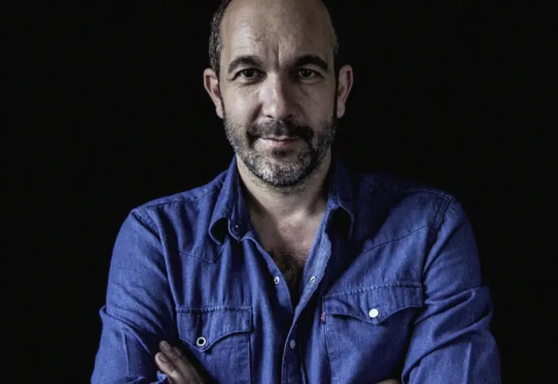 Hombre con barba y camisa vaquera azul, mirada directa. Podría ser DJ Coco listo para pinchar.