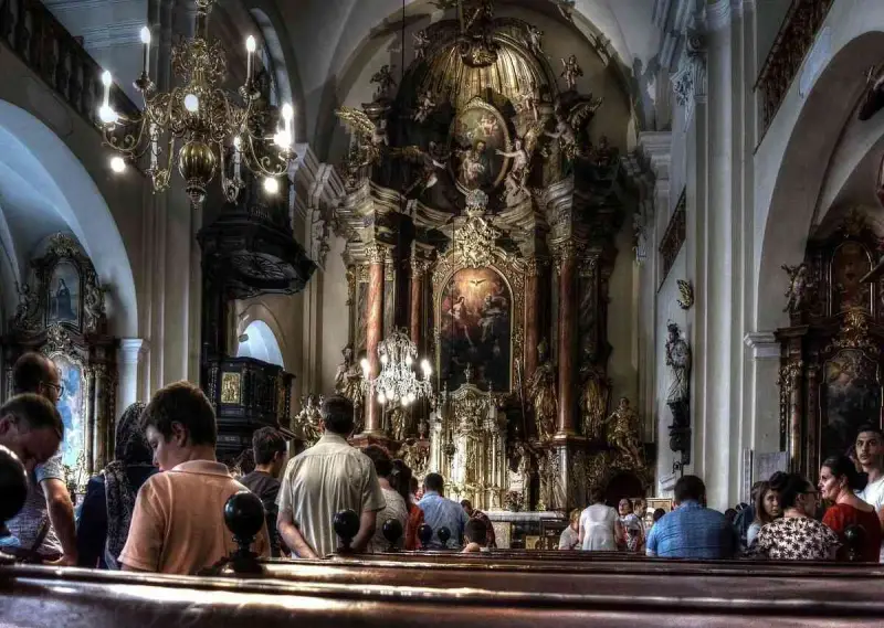 Wnętrze kościoła z bogato zdobionym ołtarzem. Ludzie siedzą w ławkach, słuchając kazania. Czy to czas na gorzkie żale?