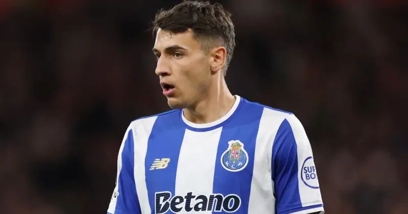 Piłkarz w niebiesko-białej koszulce FC Porto, gdzie gra Kiwior, z uwagą obserwuje boisko.
