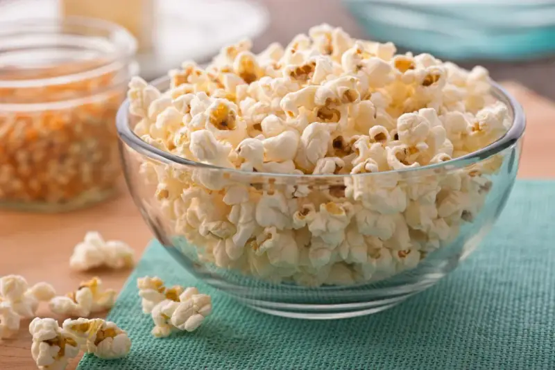 Misternie ułożony popcorn w szklanej misce. Czy popcorn jest zdrowy? To zależy od sposobu przygotowania, ale sam w sobie jest dobrym źródłem błonnika.