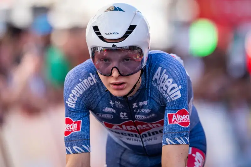 Juri Hollmann im Zeitfahr-Outfit, konzentriert auf der Strecke. Das blaue Trikot mit Alpecin-Logo und die aerodynamische Kopfbedeckung sind gut erkennbar.