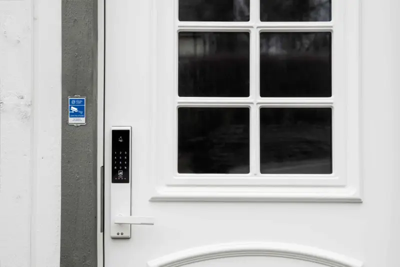 Vit ytterdörr med digitalt lås, låsklass 3, och en skylt för larm med åtgärd.