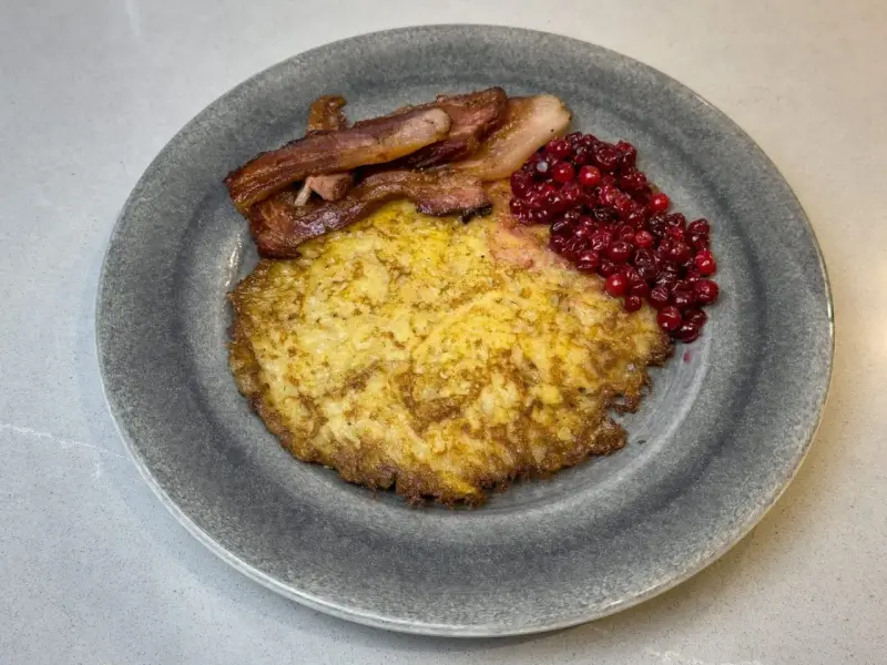 En tallrik med raggmunk, stekt fläsk och lingon. Ett klassiskt svenskt raggmunk recept som är perfekt för en mysig middag.