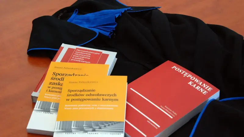 Książki o prawie karnym i togi prawnicze. Wiedza o prawach przysługujących oskarżonemu w sądzie jest kluczowa.