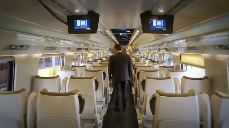 Wnętrze pociągu Pendolino. Para pasażerów idzie przez pusty wagon w drodze z Rzeszowa do Gdańska.