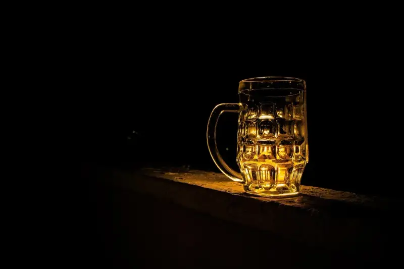 Szklanka piwa Kozel Černý, złociste światło odbija się w jej ściankach.
