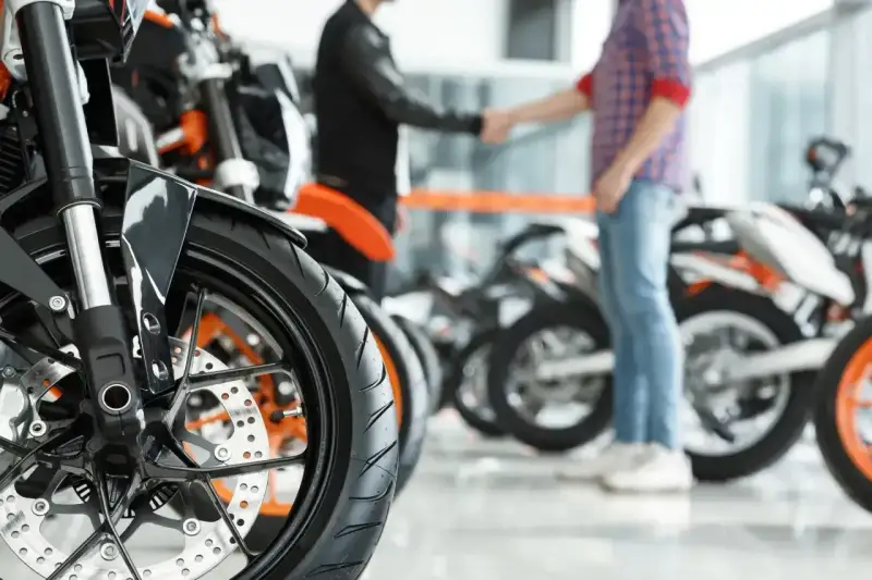 Dwóch mężczyzn ściska sobie dłonie przy motocyklach. Sfinalizowali sprzedaż motocykla przed upływem 6 miesięcy.