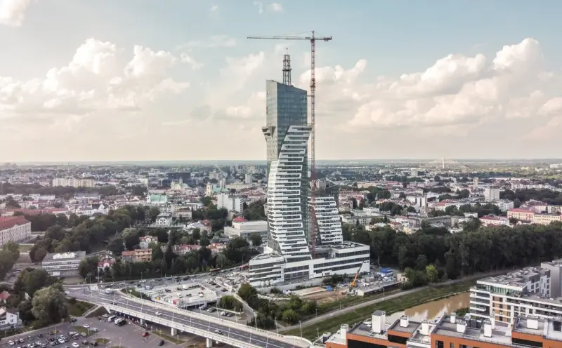 Wielka, kręcona wieża góruje nad miastem. To najwyższy budynek mieszkalny w Polsce, wciąż w budowie, z dźwigiem na szczycie.