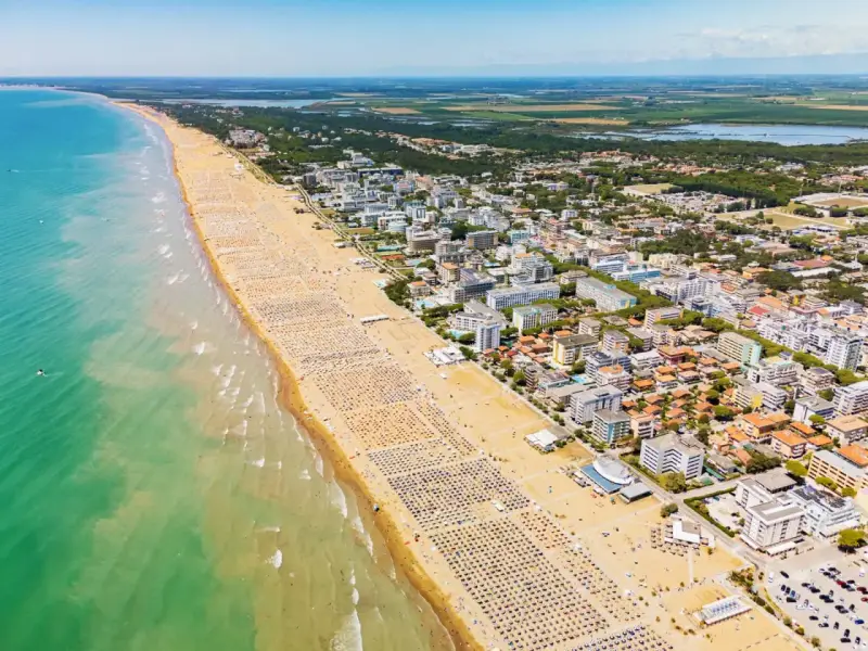 Słoneczna bibione plaża tętni życiem. Tysiące leżaków i parasoli tworzy barwny dywan, a turkusowe morze zaprasza do kąpieli.