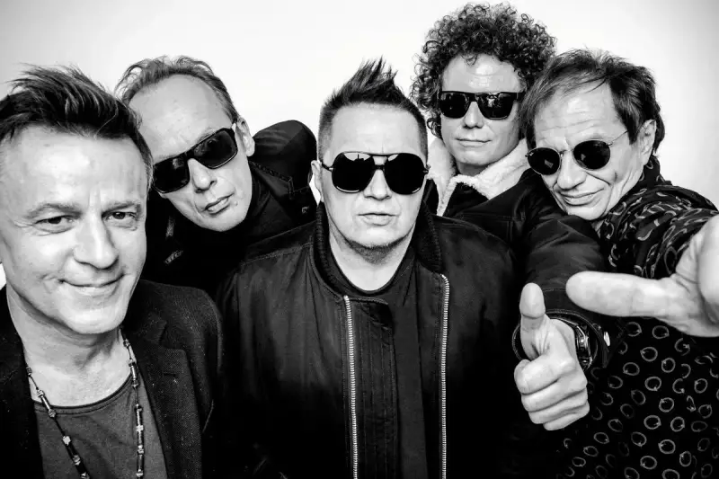 Pięciu mężczyzn w okularach przeciwsłonecznych, gotowych na koncert. Jeden z nich pokazuje kciuk w górę, jakby mówił "t.love hau! hau!".