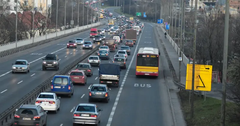 Autobus jedzie pasem dla autobusów. Wokół ruch samochodowy.