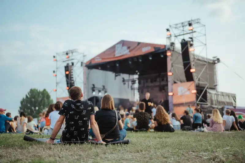 Widownia siedzi na trawie przed sceną podczas Enea Festival Baranowo.
