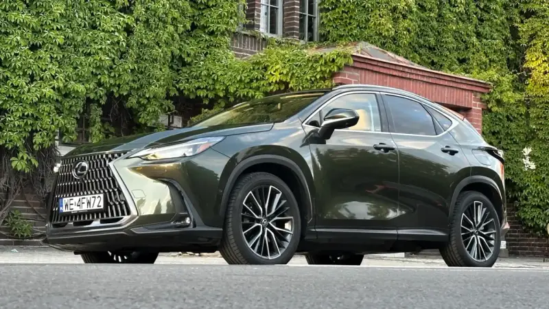 Ciemnozielony Lexus NX 450h+ plug-in zaparkowany przed budynkiem porośniętym bluszczem.