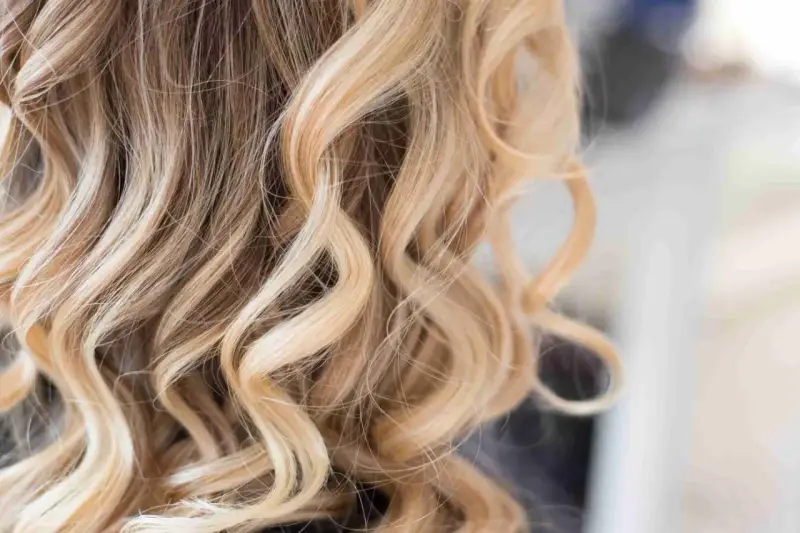 Falujące włosy z pasemkami blond z jasnym brązem, tworzące efekt słonecznych refleksów.