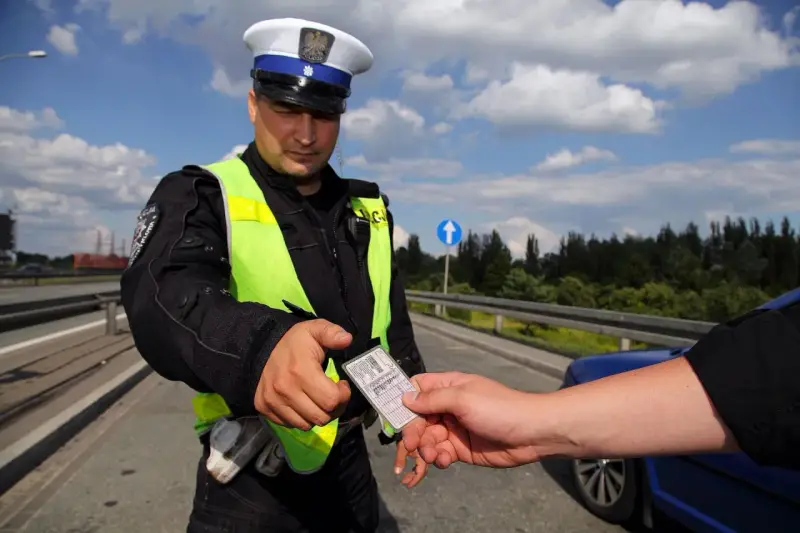 Policjant w kamizelce odblaskowej prosi o okazanie dokumentów. Czy trzeba mieć przy sobie prawo jazdy? Tak, podczas kontroli drogowej.