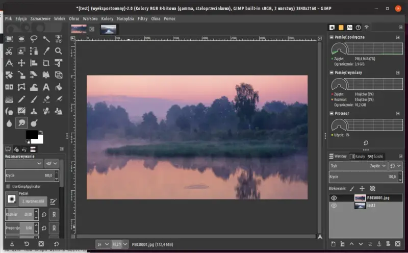 Mglisty poranek nad rzeką, edytowany w **GIMP 2.10**. Widać odbicie drzew w wodzie i wschód słońca.