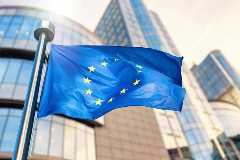 Bandiera europea sventola davanti a edifici moderni, simbolo di unità e di un futuro con un **grant significato economia** per il continente.