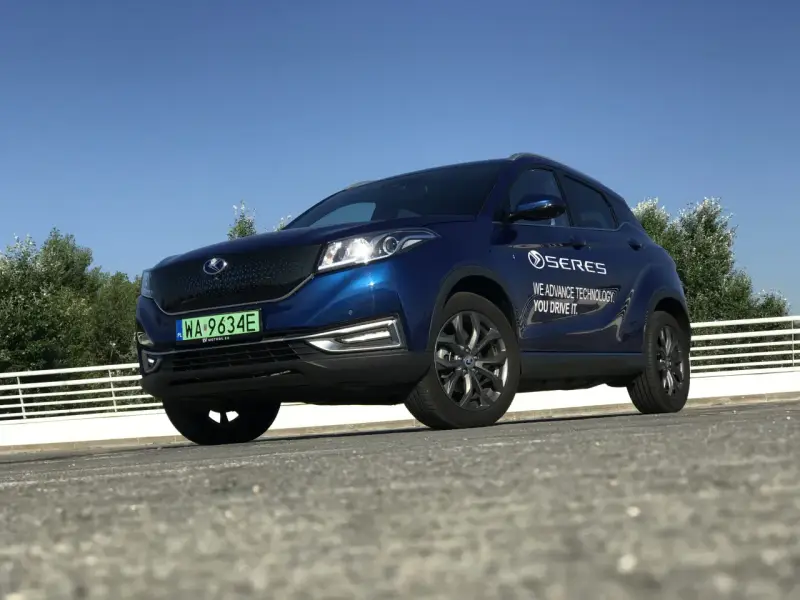Niebieski SUV Seres 3 zaparkowany na zewnątrz, z widocznym logo i napisem.