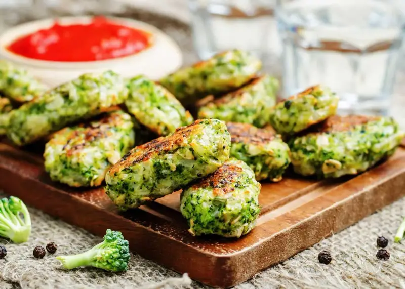 Deliciosas bolitas de brócoli, perfectas para tus recetas con brócoli. Servidas con salsa roja y un toque de pimienta.