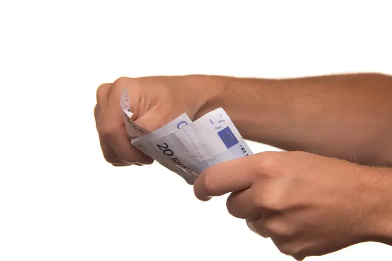 Dłonie trzymają banknoty euro. To może być symboliczne zawiadomienie o uchyleniu zajęcia, gdy pieniądze wracają do właściciela.