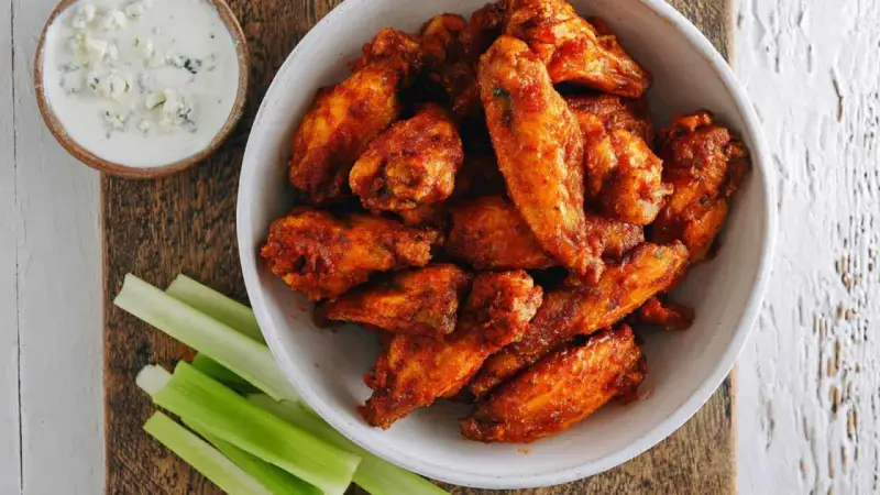 Chrupiące skrzydełka z airfryer w misce, obok sosu serowego i łodyg selera. Idealna przekąska!