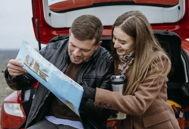 Para planować podróż i ubezpieczenie samochodu na wyjazd za granicę, para przegląda mapę.
