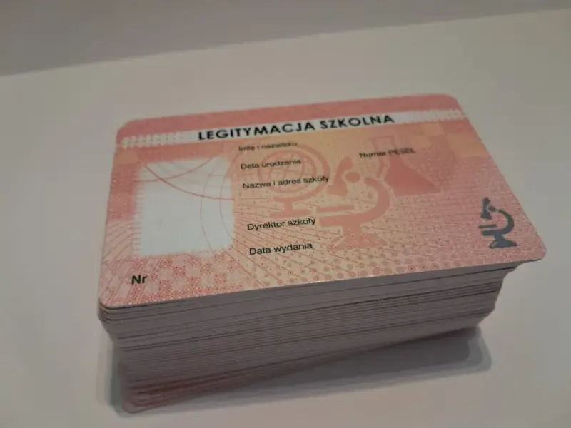 Stos nowych legitymacji szkolnych z miejscem na zdjęcie i danymi ucznia.