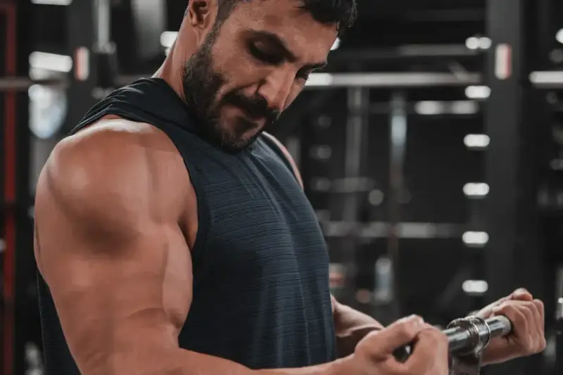 Mężczyzna ćwiczy biceps na siłowni. Zastanawia się nad cytrulina skutki uboczne, ale skupia się na treningu.