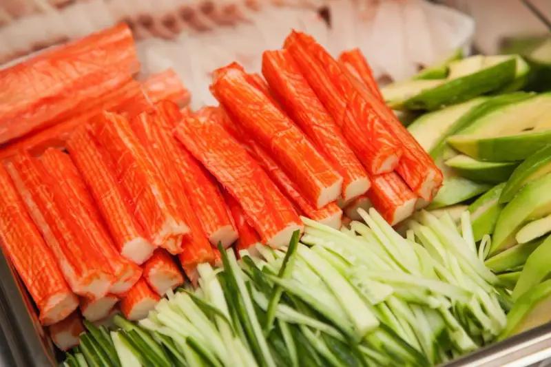 Paluszki surimi, pokrojony ogórek i awokado. Idealne składniki do sushi, które wyjaśniają, surimi co to jest.