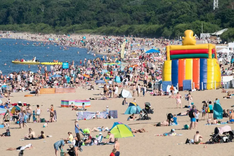 Tłum ludzi na plaży, dmuchany zamek, łodzie na wodzie – wakacje all inclusive Polska w pełni!