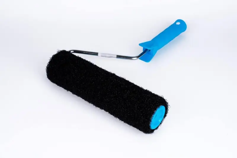 En svart roller med blått handtag, perfekt för att applicera rullspackel jämnt på väggar.