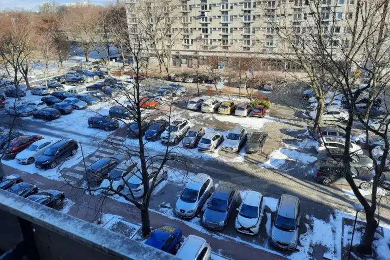 Zimowy parking pod blokiem z lat 90. pokazuje, dlaczego mieszkańcy mają problem z parkowaniem. Auta upchnięte na każdym wolnym skrawku ziemi.