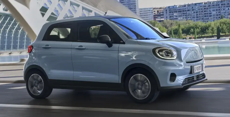 Jasnoszary Leapmotor T03 na tle nowoczesnej architektury. Sprawdź, jaka jest leapmotor t03 cena i czy to auto dla Ciebie.