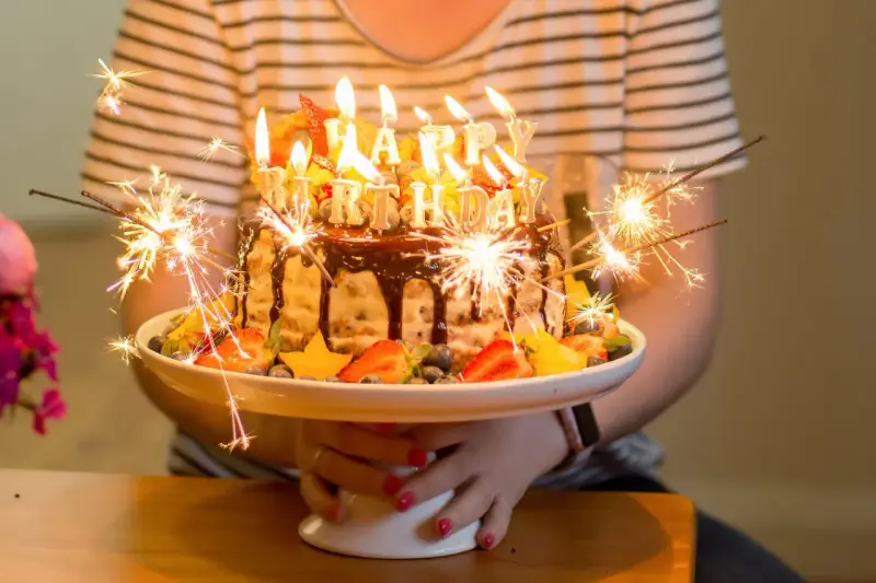 Urodzinowy tort z ogniem i owocami, idealny na mądre życzenia urodzinowe dla zięcia.