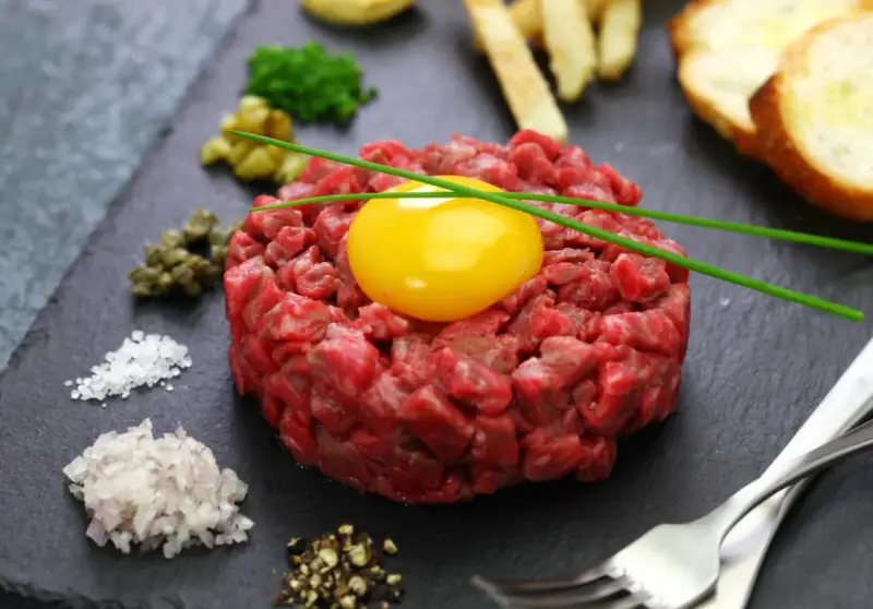 Tartare di manzo fresca e succulenta, con tuorlo d'uovo, capperi, cipolla, sale, pepe e crostini.