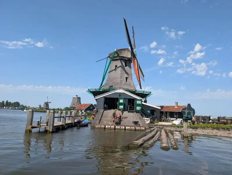 Wiatraki w Zaanse Schans nad wodą, z drewnianym pomostem i łódkami.