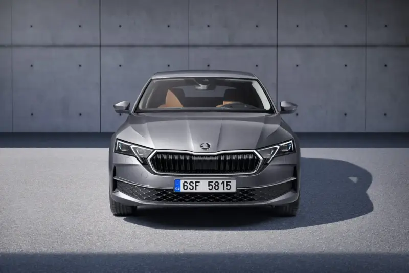 Nowa Skoda Octavia w szarym kolorze, z brązowym wnętrzem, prezentuje się elegancko na tle betonowej ściany.