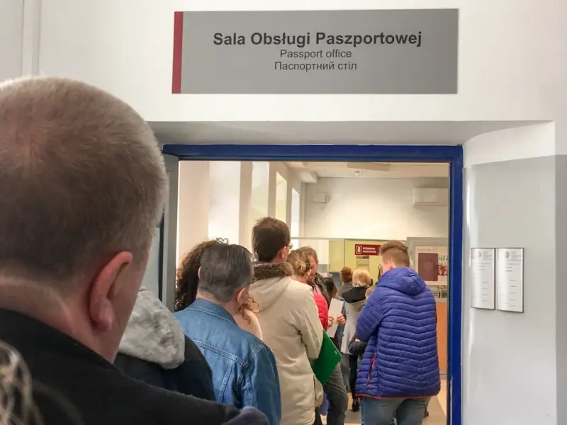 Kolejka do sali obsługi paszportowej. Czy odbiór paszportu musi być osobiście? Ludzie czekają w środku i na zewnątrz.