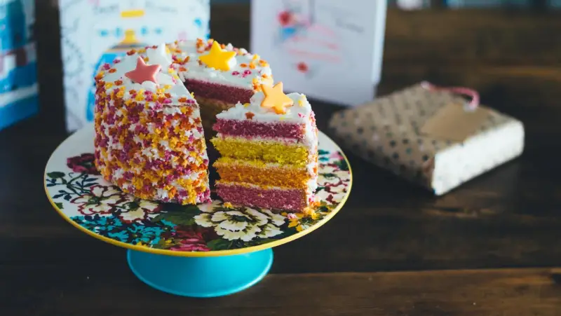 Pastel de capas arcoíris con estrellas de azúcar y chispas. ¡Ideas para decorar tartas que inspiran alegría y color!