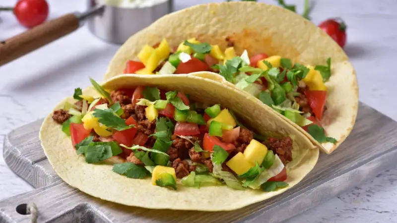 Dwa pyszne, domowe fast foody: tortille z mielonym mięsem, pomidorami, papryką, mango i świeżą kolendrą.