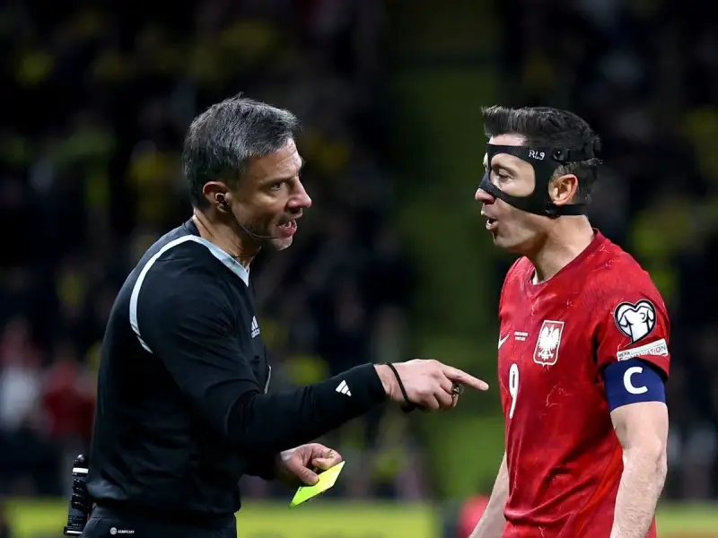 Sędzia pokazuje żółtą kartkę Robertowi Lewandowskiemu, jednej z legend piłki nożnej.