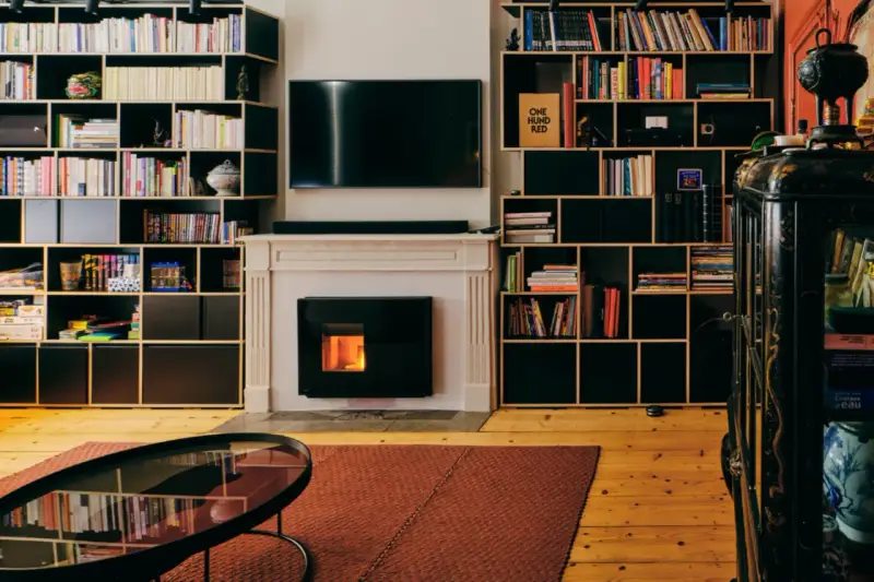 Salon cosy avec cheminée et insert à pellets silencieux, entouré d'étagères remplies de livres.