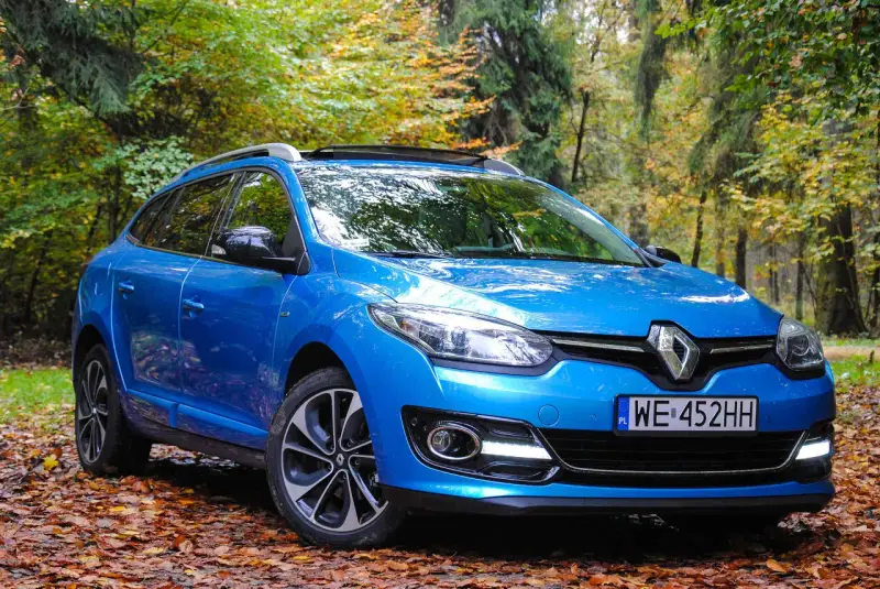 Niebieski Renault Megane 2 1.6 16v na tle jesiennego lasu.