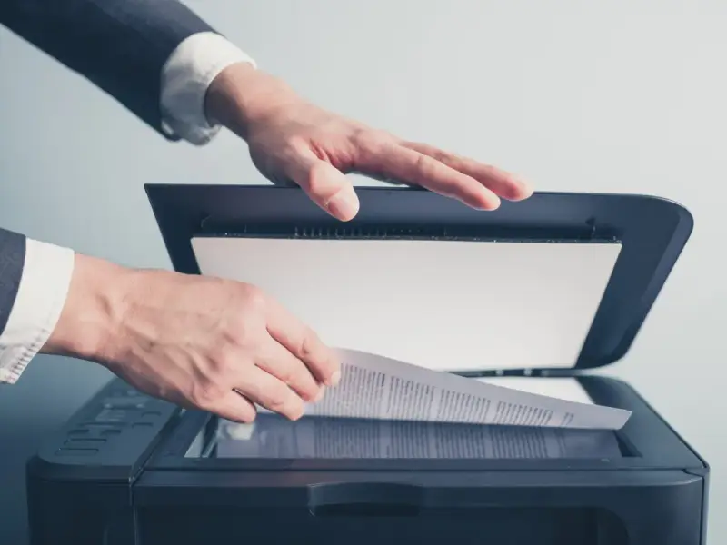 Un homme en costume utilise un scanner ged pour numériser un document important.