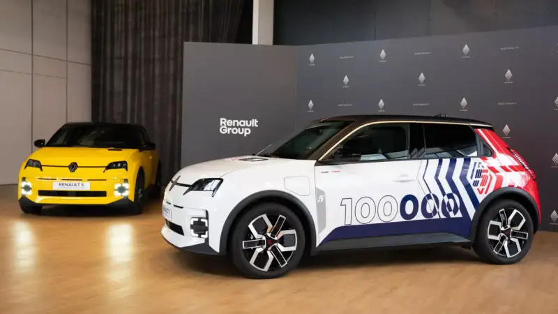 Deux Renault 5 électriques, une jaune et une blanche décorée pour un essai, présentées devant le logo Renault Group.