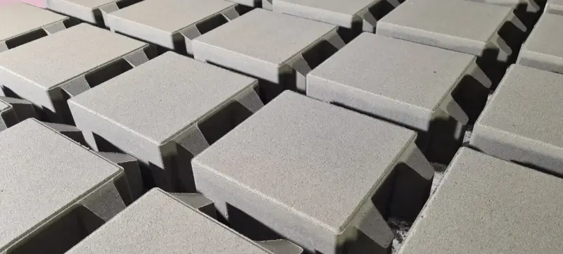 Szare, betonowe kostki brukowe ułożone w rzędach, gotowe do budowy ścieżki. Różne rodzaje kostki brukowej czekają na zastosowanie.