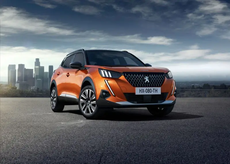 Pomarańczowy Peugeot 2008 na tle miasta. Sprawdź jego wymiary i możliwości.