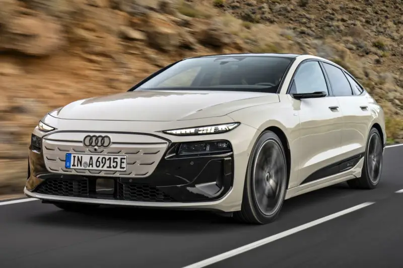 Jasnoszary Audi A6 e-tron z czarnymi akcentami jedzie po drodze.
