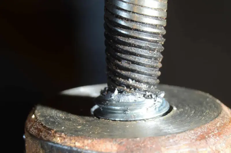 Uszkodzona śruba w aluminiowej obudowie. Widoczne ślady po próbie wykręcenia urwanej śruby z aluminium.